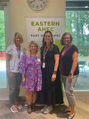 4 women in front of the Eastern AHEC sign 